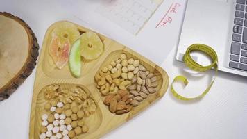 Preparing a diet plan from dried fruits. Healthy lifestyle. Woman looks at her laptop and prepares a diet list. video