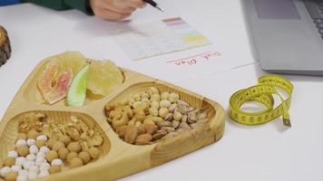 Preparing a diet plan from dried fruits. Healthy lifestyle. Woman looks at her laptop and prepares a diet list. video