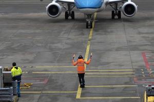 an operator helping pilots of airplane while parking at the terminal photo