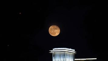 The moon just rising up in the city at night photo