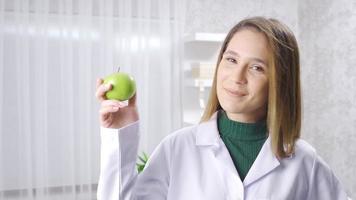 positif diététicien femme recommande en bonne santé alimentaire, spectacles Frais pommes. diététicien soulignant le consommation de des légumes et des fruits pour une en bonne santé régime. video