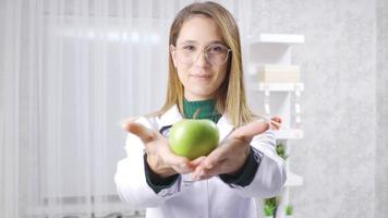 positivo dietista mulher é mostrando verde maçã para saudável comendo. dietista enfatizando a consumo do legumes e frutas para uma saudável dieta. video