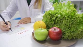 nutritionniste médecin prépare une régime plan pour une en bonne santé vie. diététicien femme en train de préparer une légume et fruit basé régime planifier.