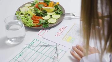diététicien en train de préparer en bonne santé légume salade et régime planifier. une diététicien femme prépare une régime plan pour une en bonne santé vie. video