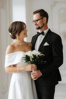 groom in a black suit tie and the bride in a bright studio photo