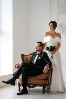 groom in a black suit tie and the bride in a bright studio photo