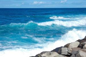 grande olas estrellarse en contra el rocas en el Oceano foto