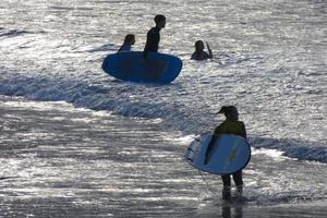 Surfers getting ready to enter the water and walking with the board along the shore. photo