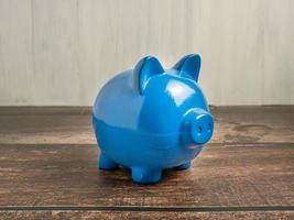 The blue piggy bank on wood table for earn or saving concept photo