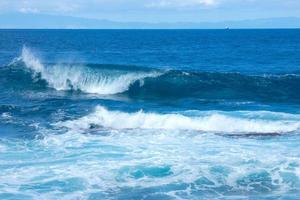 grande olas estrellarse en contra el rocas en el Oceano foto