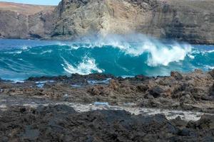 grande olas estrellarse en contra el rocas en el Oceano foto