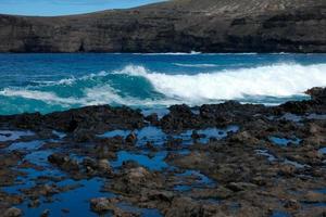 grande olas estrellarse en contra el rocas en el Oceano foto