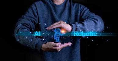 A person stretches out his hand with a model of a robot on his palm. It represents the use of AI and Robotic systems to research and work. photo