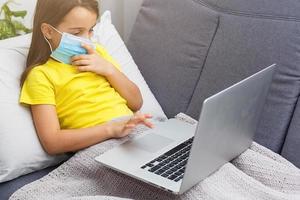 little girl in a protective mask at distance home schooling, quarantine photo