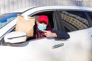 delivery man delivers orders by car. Delivery service under quarantine, disease outbreak, coronavirus covid-19 pandemic conditions. photo