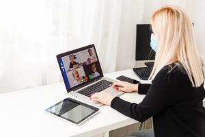 Young woman wearing protective gloves on hands and mask on face working from home or at office work by the laptop video call preventing virus spread epidemic quarantine prevention photo