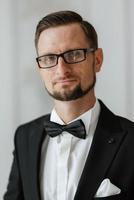 groom in a black suit with a bow photo