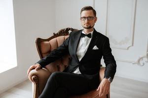 portrait of a groom in a black suit and glasses in a studio photo