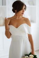 brunette bride in a tight wedding dress in a bright studio photo