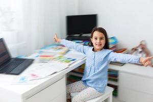 education and school online concept - smiling little student girl with many books at home schooling photo