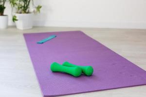 Unrolled yoga mat on wooden floor in modern fitness center or at home with big windows and white brick walls, comfortable space for doing sport exercises, meditating, yoga equipment photo