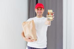 papel bolsillo y comida contenedores en manos de un sonriente repartidor. calidad Servicio de un restaurante. foto