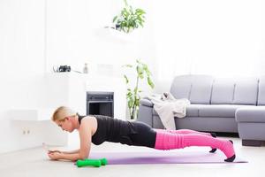 Concept of healthy lifestyle. Close up of young woman hands rolling violet yoga fitness mat before working out at home in living room. Every day morning ritual. Wooden floor, soft light photo