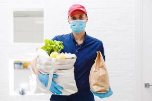 Courier's hands in latex white medical gloves deliver parcels in food packages to the door during the epidemic of coronovirus, COVID-19. Safe delivery of online orders during the epidemic. photo