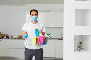 cleaning, health and hygiene concept - indian man wearing protective medical mask for protection from virus disease in gloves with detergent and mop at home photo