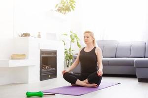 a thin European girl doing stretching exercises at home on a yoga mat, rays of light shine from the window. flare. quarantine sport. photo