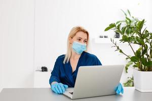 Young business woman working from home, wearing protective mask photo