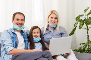 Quarantine time Family in protective masks at living room together. photo