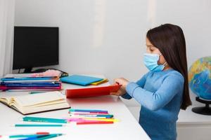 little girl in a protective mask at distance home schooling, quarantine photo