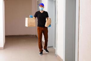 Delivery man holding cardboard boxes in medical rubber gloves. Quarantine. Coronavirus. door delivery photo