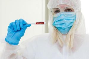 Researcher in hazmat protective suit examining a test tube in the chemical lab. photo