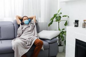 enfermo hombre en un máscara y guantes mentiras en cama a hogar foto