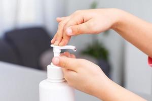 little girl applying antibacterial antiseptic gel on hands anti bacteria viruses in studio on white background. baby epidemic protection, close-up photo