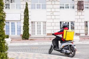 Contactless food delivery to customers home. Delivery service worker with thermal backpack quick delivering food at doorstep in quarantine from restaurant, supermarket or cafe . Online ordering food photo