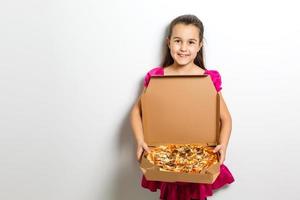 contento pequeño niña con Pizza en un papel caja foto