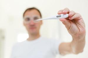 people, healthcare and fever concept, man, thermometer over grey background photo