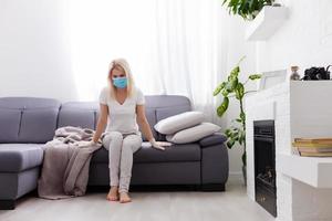 Portrait of a sick woman alone . An infectious agent protection gear including a mask. An sick older woman wearing protective masks to protect against virus. Coronavirus. Quarantine at home. photo