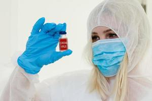 Researcher in hazmat protective suit examining a test tube in the chemical lab. photo