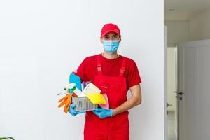 man wearing protection mask and holding basket with cleaning supplies, on white background photo