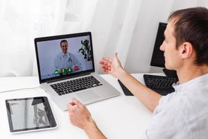 Man Having Video Chat With Doctor On Laptop At Home photo