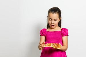 Cute little Indian Asian girl child eating tasty Pizza. Standing isolated over white background. photo