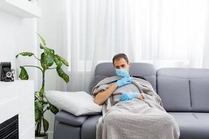 sick man in a mask and gloves lies in bed at home photo