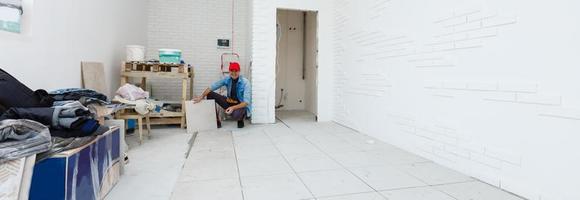 master is installing floor ceramic tile in a room, pressing down and leveling, interior finishing of premises of a living houses photo