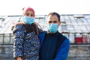 Father and daughter wearing respirator masks staying together in early spring, outdoor lifestyle, guideline in quarantine time photo