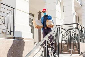 food delivery man with bags in a protective mask on his face photo