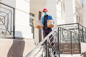 comida entrega hombre con pantalones en un protector máscara en su cara foto